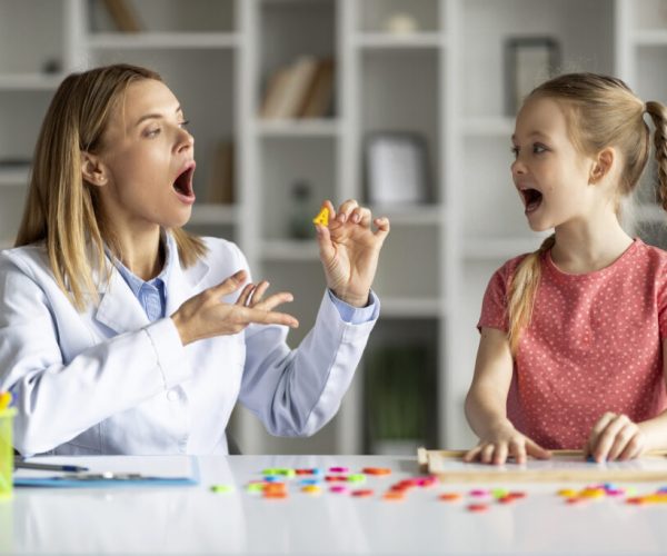 Effective Speech Therapy. Therapist Lady Having Lesson With Cute Little Girl, Professional Logopedist Teaching Articulation Of Letter A To Female Child, Improve Kid's Language Via Interactive Games